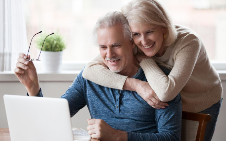 Man en vrouw kijken samen op hun laptop die op de tafel staat
