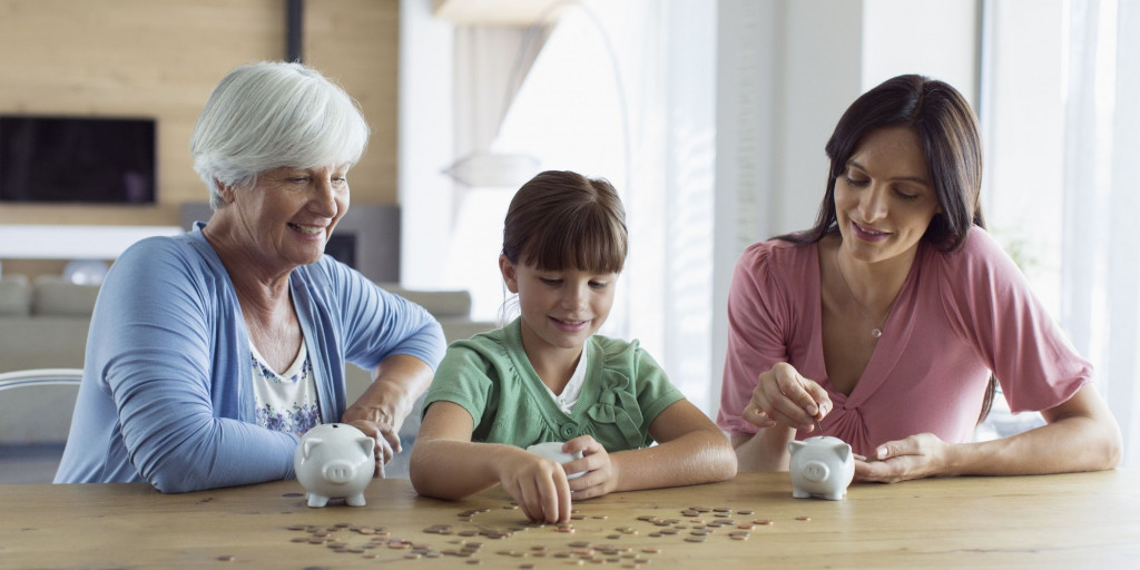 Grootmoeder met kleinkind en dochter aan een tafel waarop een spaarpot staat