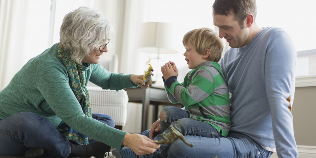 Oma speelt met kleinzoon die op de schoot van zijn papa zit