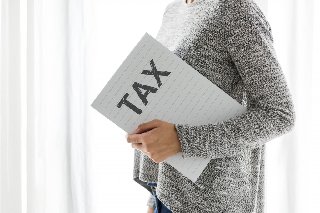 Vrouw met kaft waarop tax staat geschreven