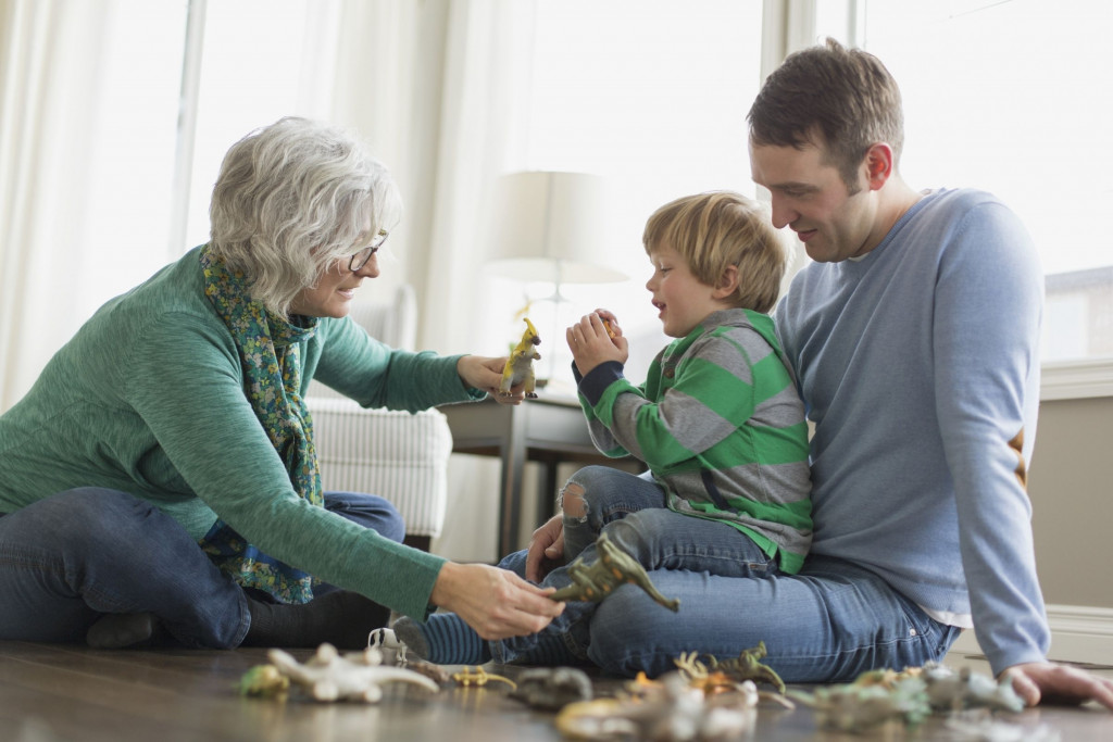 Oma speelt met kleinzoon die op de schoot van zijn papa zit
