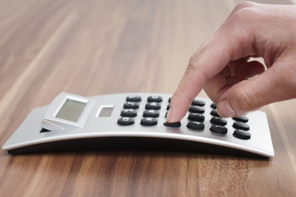 Hand tikt op rekenmachine die op tafel ligt